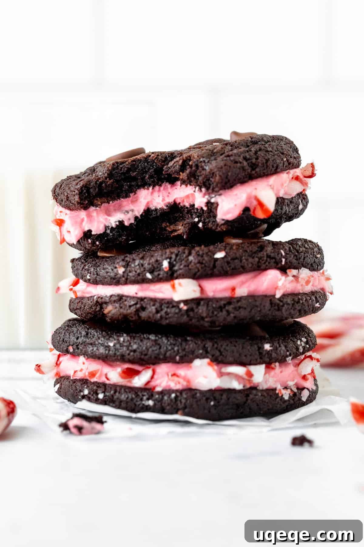 Rich Chocolate Peppermint Creme Cookies 3 Three chocolate candy cane sandwich cookies, stacked on top of each other, with a delicious bite taken out of the top cookie.