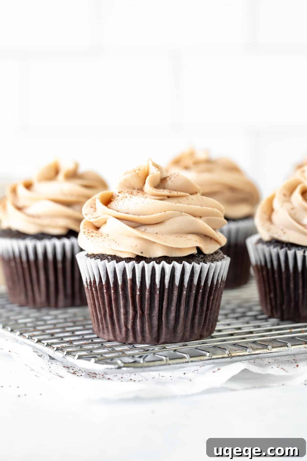 Irish Cream Dream Cupcakes 3 Freshly baked chocolate cupcakes with generous swirls of Irish cream frosting cooling on a wire rack.