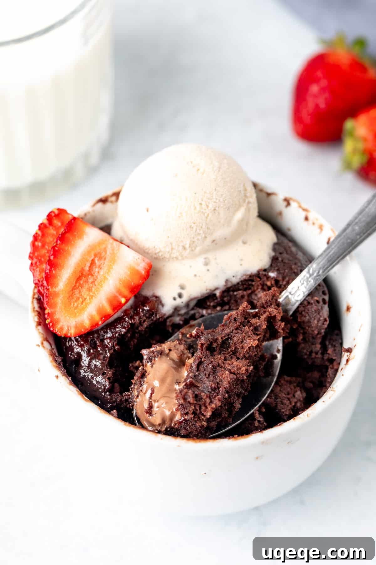 Decadent Nutella Mug Cake 2 Nutella mug cake, with a spoonful taken out, revealing a gooey center