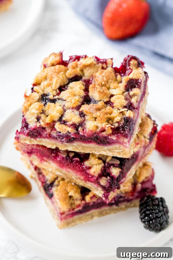 Berry Burst Crumble Squares 5 Overhead view of three mixed berry oatmeal crumble bars stacked neatly, showcasing the layers of crumble and juicy berries.