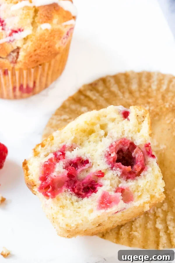 A moist, fluffy raspberry muffin, broken in half to showcase the vibrant berries nestled within its tender crumb.