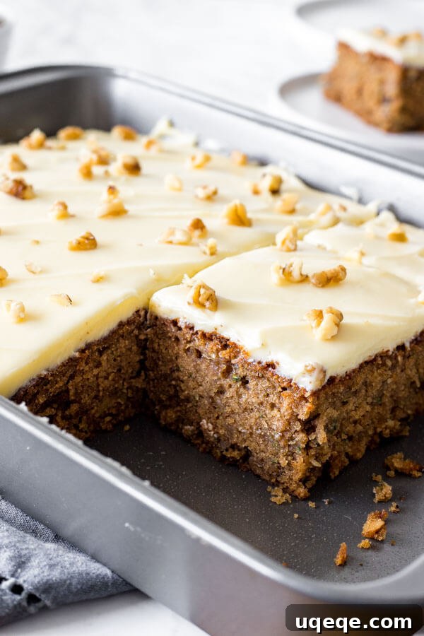 Summer Zucchini Spice Cake 3 A 9x13 inch pan of zucchini cake with cream cheese frosting with a close up of a piece that's been cut out from the pan.