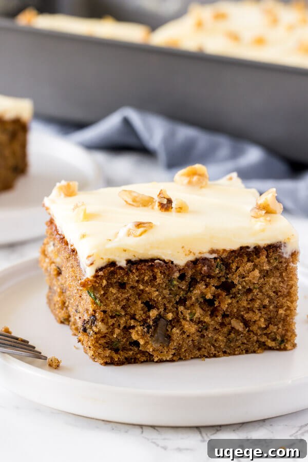 Summer Zucchini Spice Cake 4 A side angle shot of moist, tender zucchini cake with cream cheese frosting and topped with a few chopped walnuts.