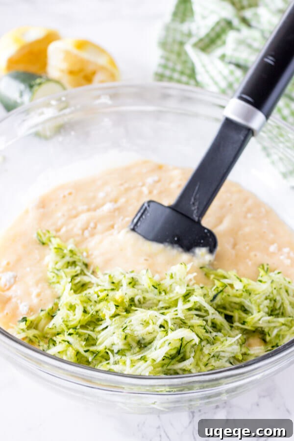 Zesty Lemon Zucchini Loaf 4 Lemon zucchini bread batter being prepared in a large mixing bowl, showcasing its smooth consistency just before the fresh grated zucchini is gently folded in.