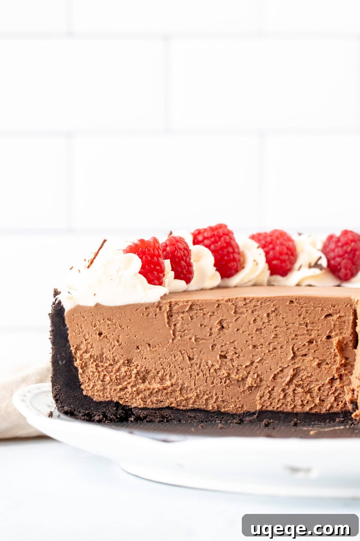 Decadent No Bake Chocolate Cheesecake 9 A generous half-portion of a rich no-bake chocolate cheesecake, adorned with fresh berries and delicate piped whipped cream, showcasing its appealing texture and perfect set.