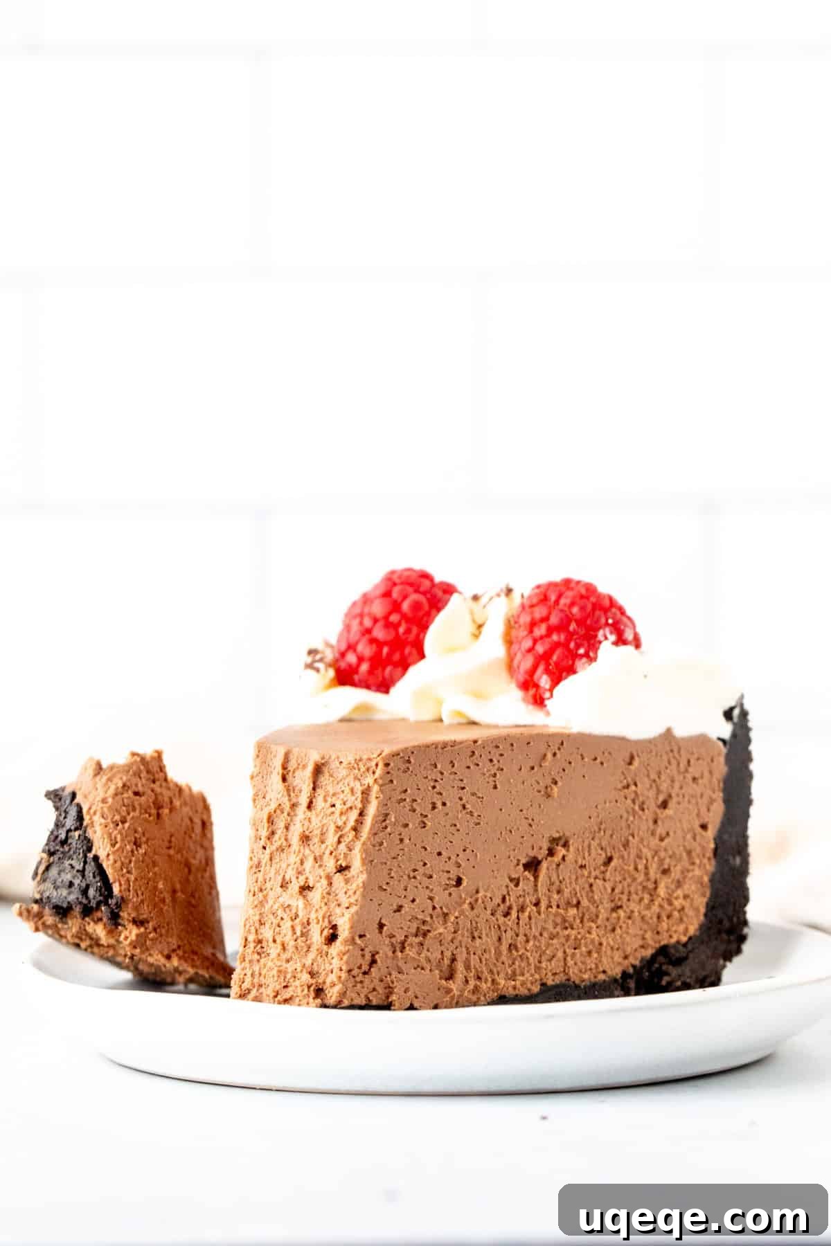 Decadent No Bake Chocolate Cheesecake 10 A close-up of a delectable slice of chocolate cheesecake with an Oreo crust, showing a bite taken out, revealing its incredibly smooth filling and crunchy base.