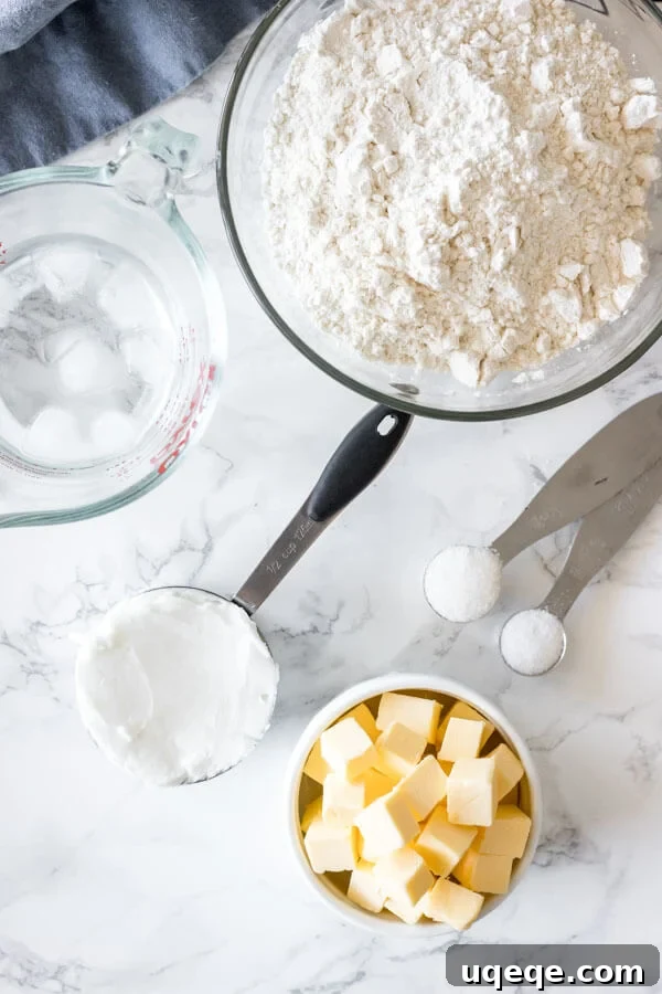 Buttery Flaky Pie Crust 3 Overhead shot of essential ingredients for making pie crust: cubed unsalted butter, solid shortening, all-purpose flour, fine salt, a pinch of sugar, and a bowl of ice water.