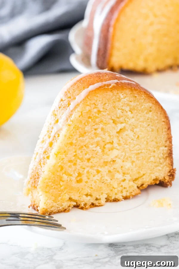 Sunshine Citrus Bundt 6 A perfectly sliced piece of moist lemon bundt cake, showing its tender crumb and a elegant drizzle of lemon glaze, served on a white plate.