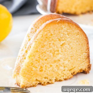 A slice of moist lemon bundt cake with a drizzle of lemon glaze on a white plate.