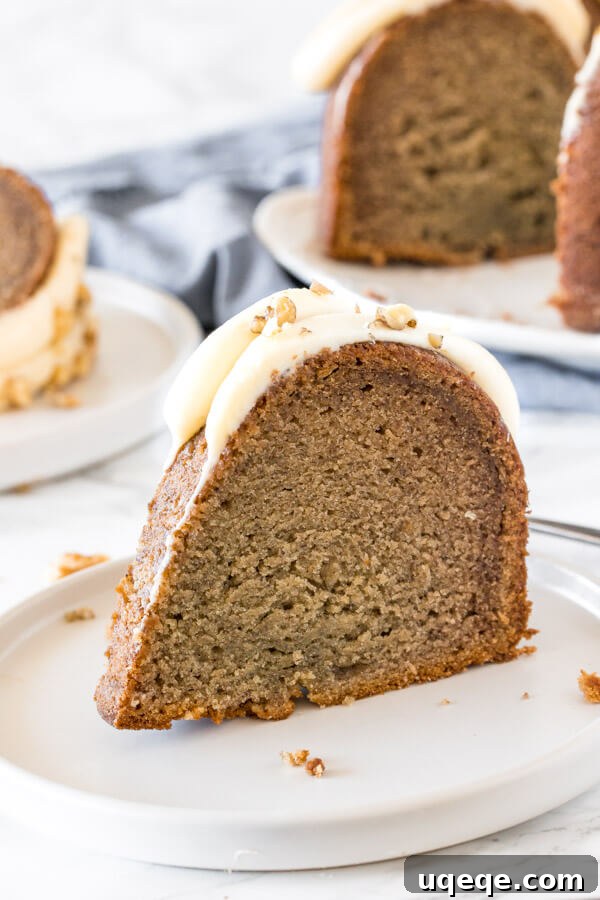 Kolayca Mükemmel Bundt Kek Yapmanın Püf Noktaları 6 A delightful slice of banana Bundt cake adorned with luscious cream cheese frosting, served on a pristine white plate.