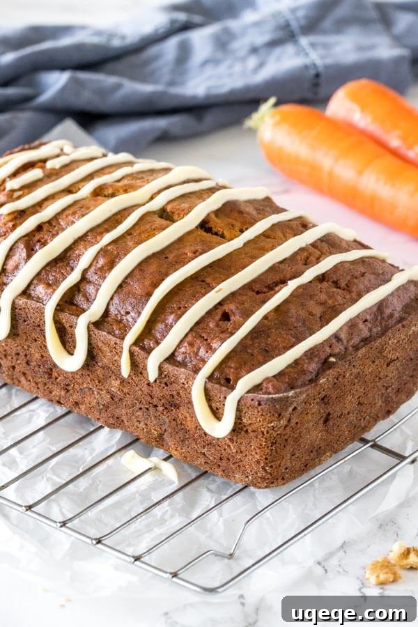 Whole loaf of banana carrot bread with a cream cheese glaze on a wire cooling rack, ready to be sliced.