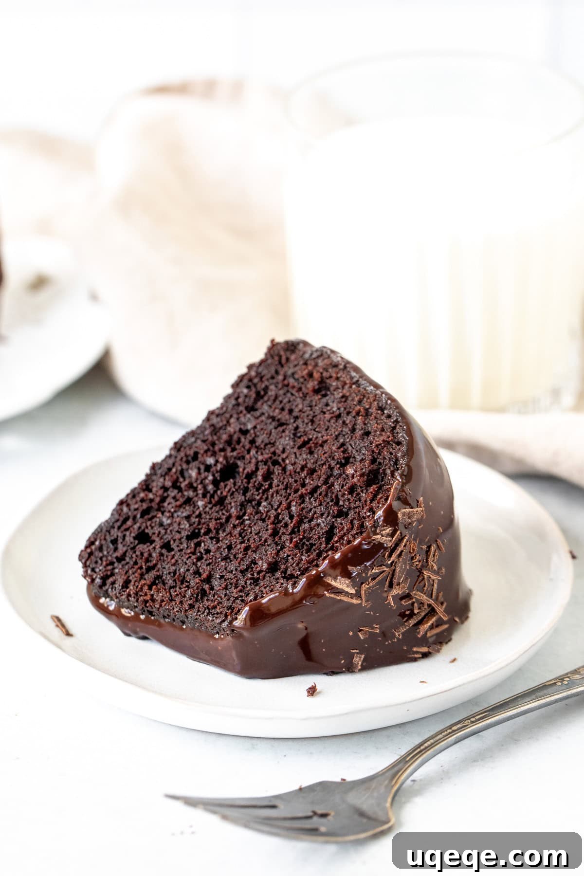 Decadent Chocolate Bundt Delight 9 A delectable slice of chocolate bundt cake with ganache, perfectly paired with a refreshing glass of milk, inviting a moment of sweet indulgence.