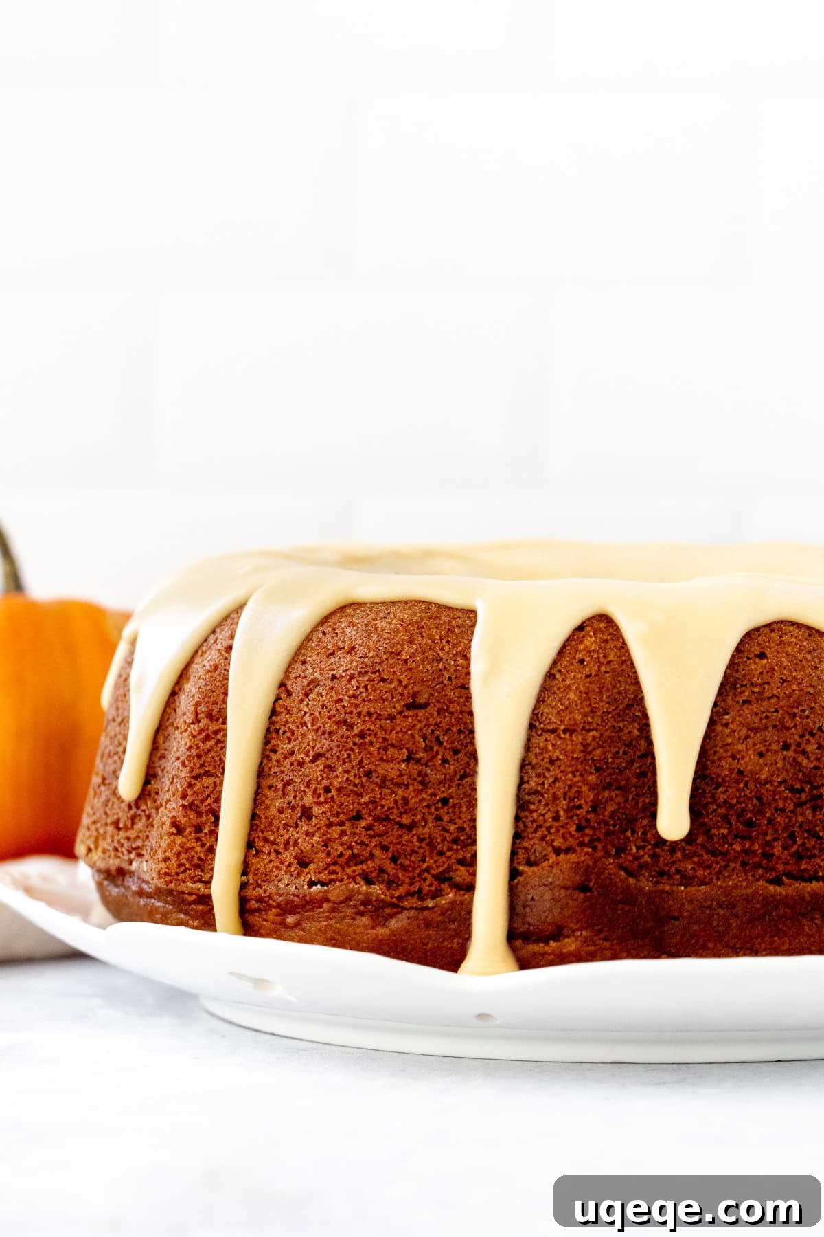 Spiced Pumpkin Bundt Delight 7 A fully baked 9-inch round pumpkin bundt cake with maple glaze poured elegantly over its ridges