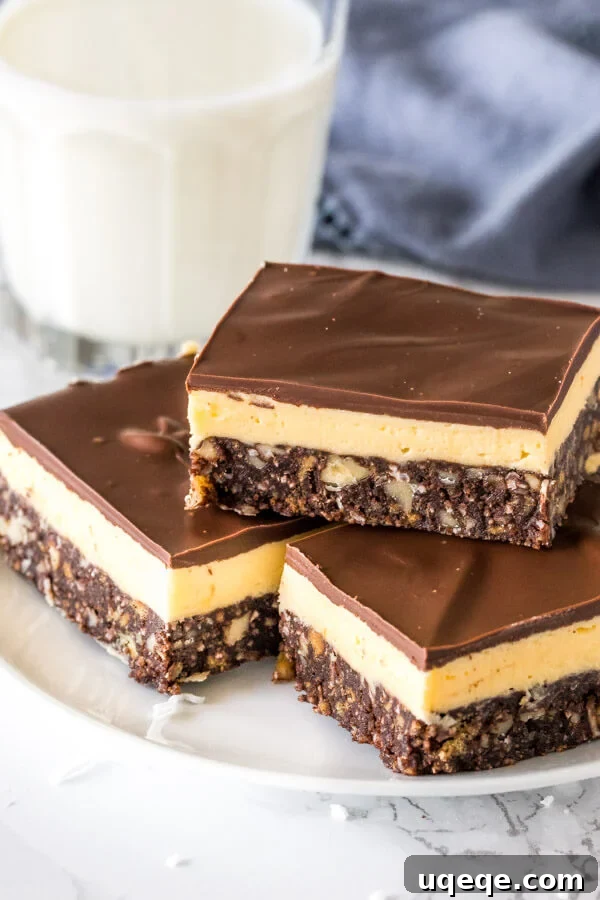 Triple Layer Nanaimo Bliss 2 A plate of classic Nanaimo bars stacked with custard buttercream filling and chocolate on top, showcasing the three distinct layers.