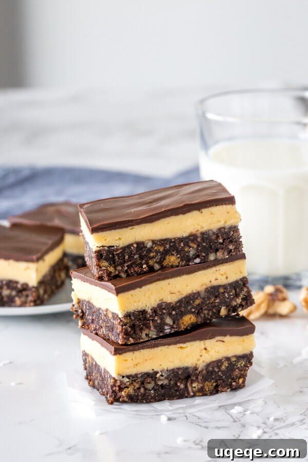 Triple Layer Nanaimo Bliss 3 A stack of three traditional Nanaimo bars showing their distinct layers on a white plate.