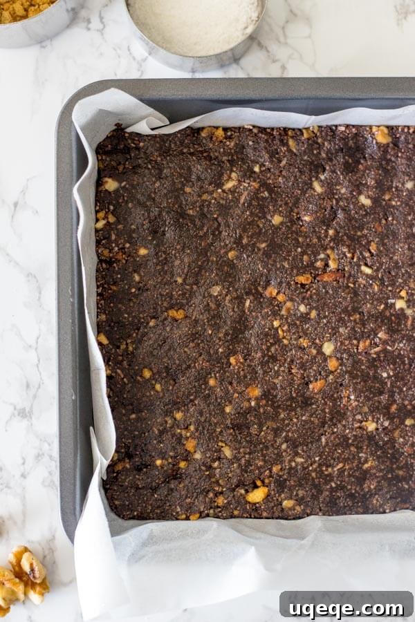 Triple Layer Nanaimo Bliss 4 Overhead shot of the chocolate coconut base for Nanaimo bars, with graham crumbs, walnuts, and coconut clearly visible, before chilling.