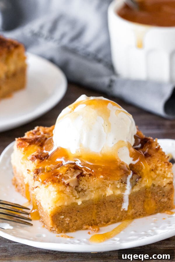 A delectable slice of pumpkin dump cake, crowned with a scoop of vanilla ice cream and drizzled with luscious caramel sauce, ready to be enjoyed.
