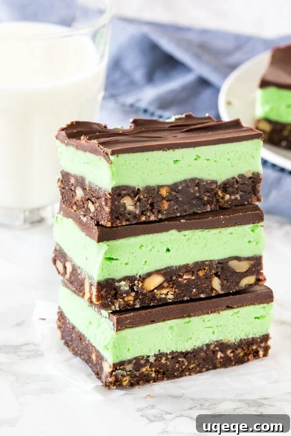 Cool Mint Nanaimo Delight 2 A stack of 3 mint Nanaimo bars shot from the side to see the 3 layers. Each layer is distinct: the dark brown base, the light green mint filling, and the shiny chocolate topping.