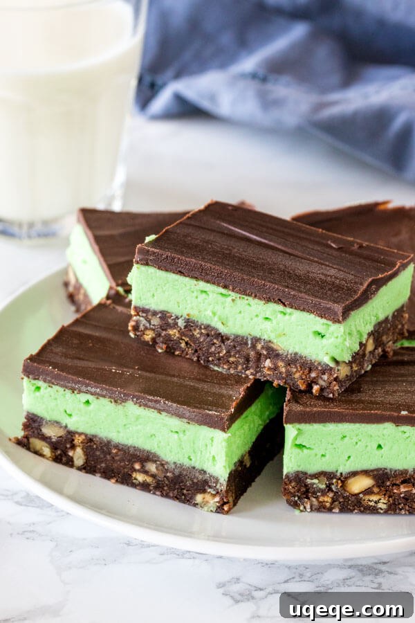 Cool Mint Nanaimo Delight 4 A plate of mint Nanaimo bars with a glass of milk. The bars are perfectly cut, showcasing their three distinct layers, and are ready to be enjoyed.