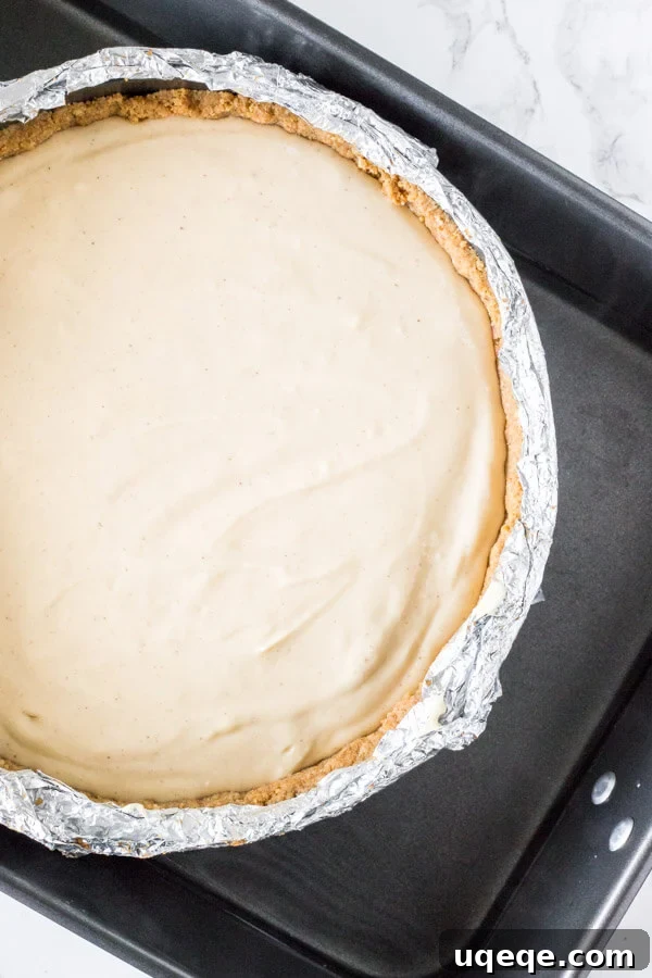 Pecan Pie Cheesecake securely placed in a water bath within a roasting pan, ready for baking.