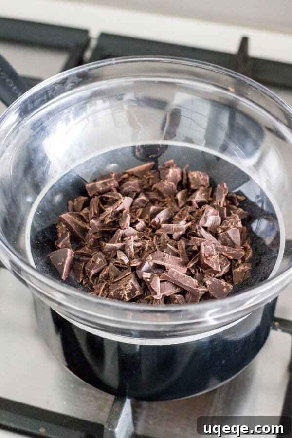 Mastering Chocolate Melting 4 Chocolate melting in a double boiler set on a stove burner, steam gently rising, ensuring indirect and even heat distribution.