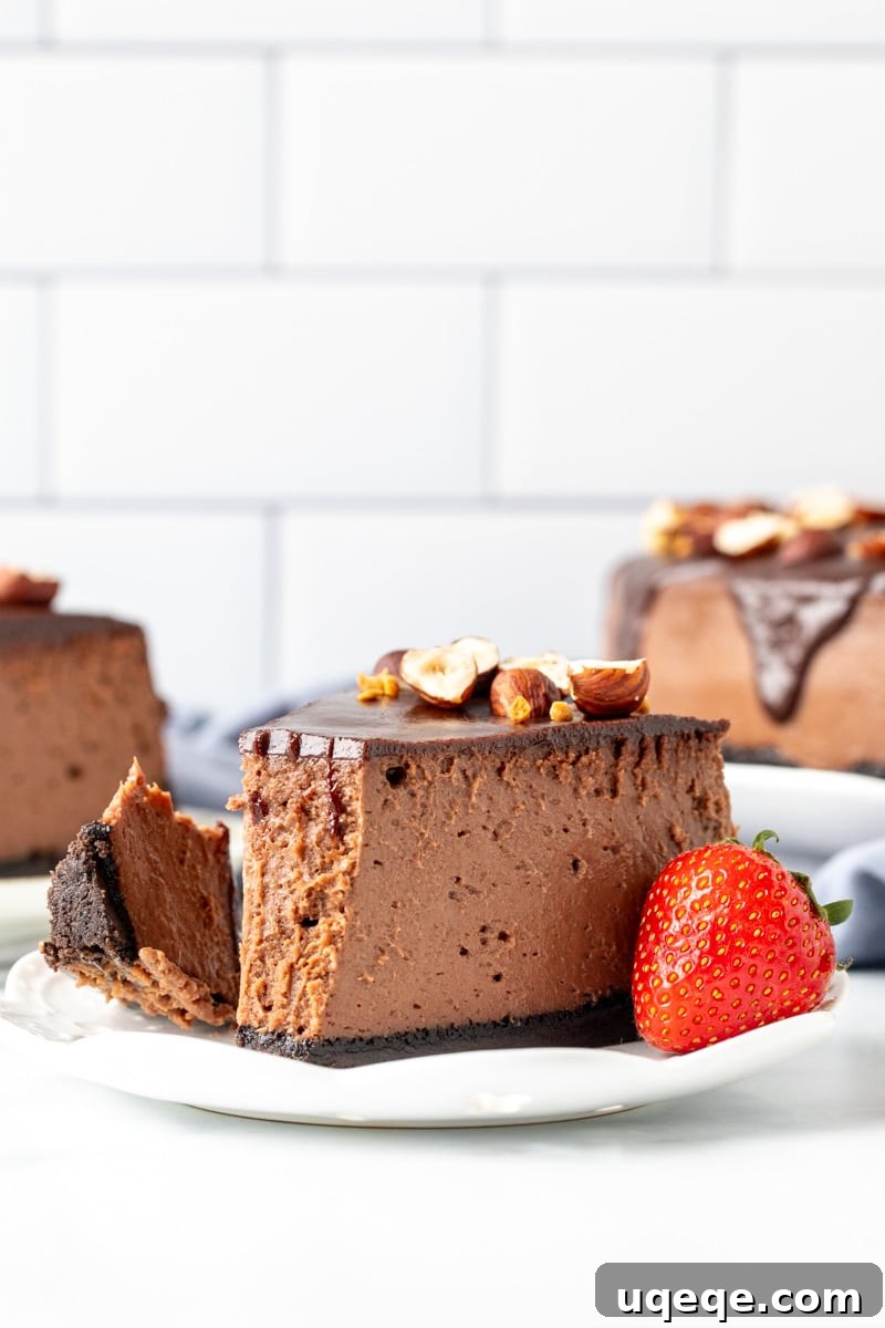 Decadent Nutella Oreo Cheesecake 9 Slice of Nutella cheesecake with bite taken out on a plate with a strawberry