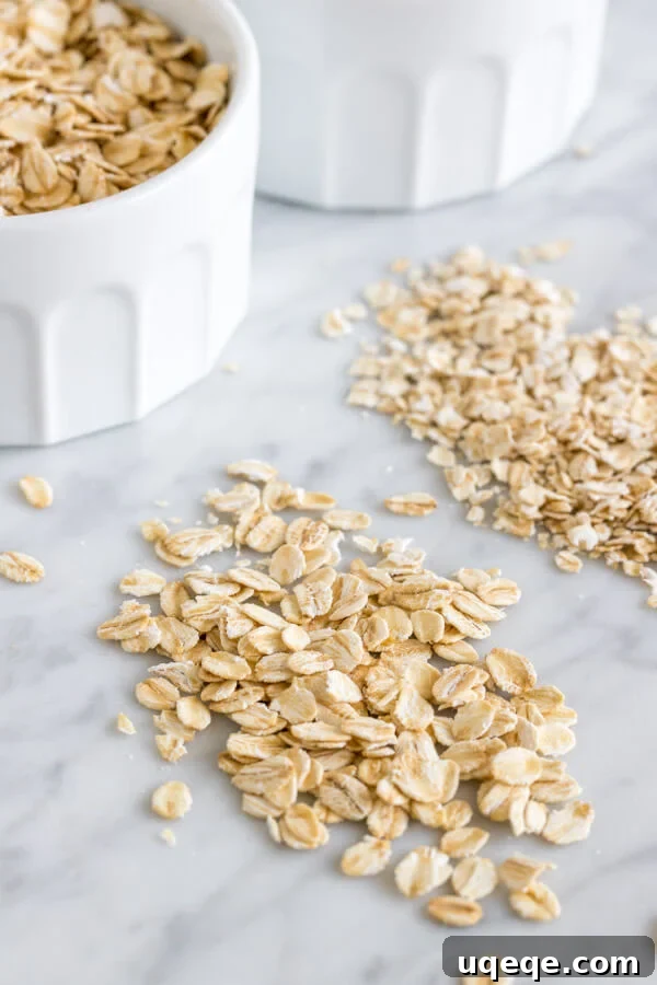 Close-up of old-fashioned rolled oats beside quick oats on a rustic marble surface, highlighting their texture differences, perfect for baking discussions.