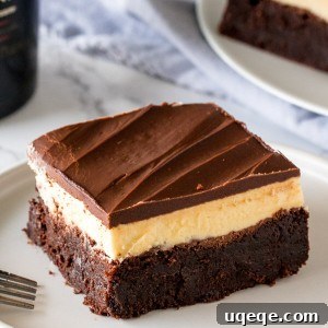 Decadent Baileys Brownies 5 A layered Baileys brownie with brownie on the bottom, Baileys frosting in the middle and chocolate ganache on top on a white plate.