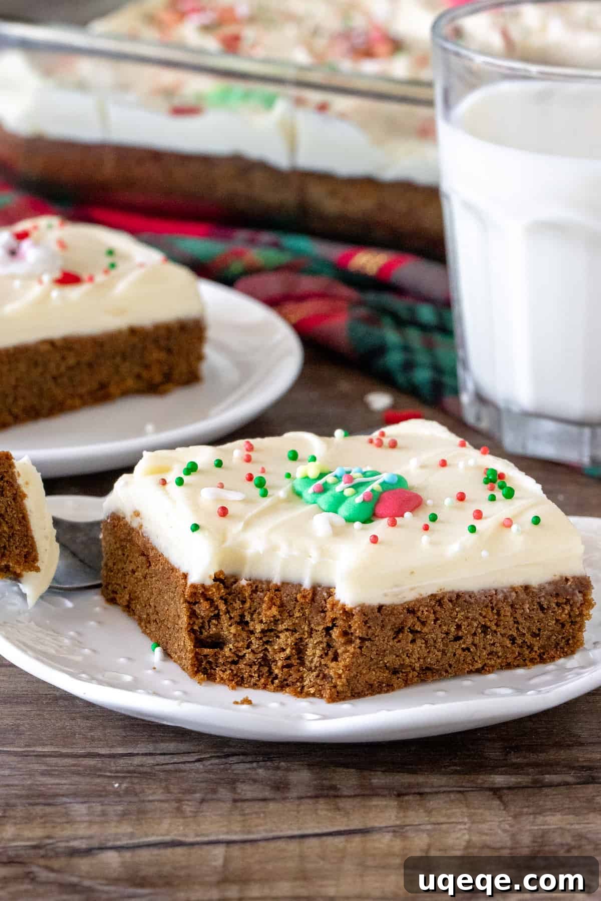 A delicious gingerbread cookie bar on a plate with a bite taken out, showcasing the soft texture and thick cream cheese frosting.