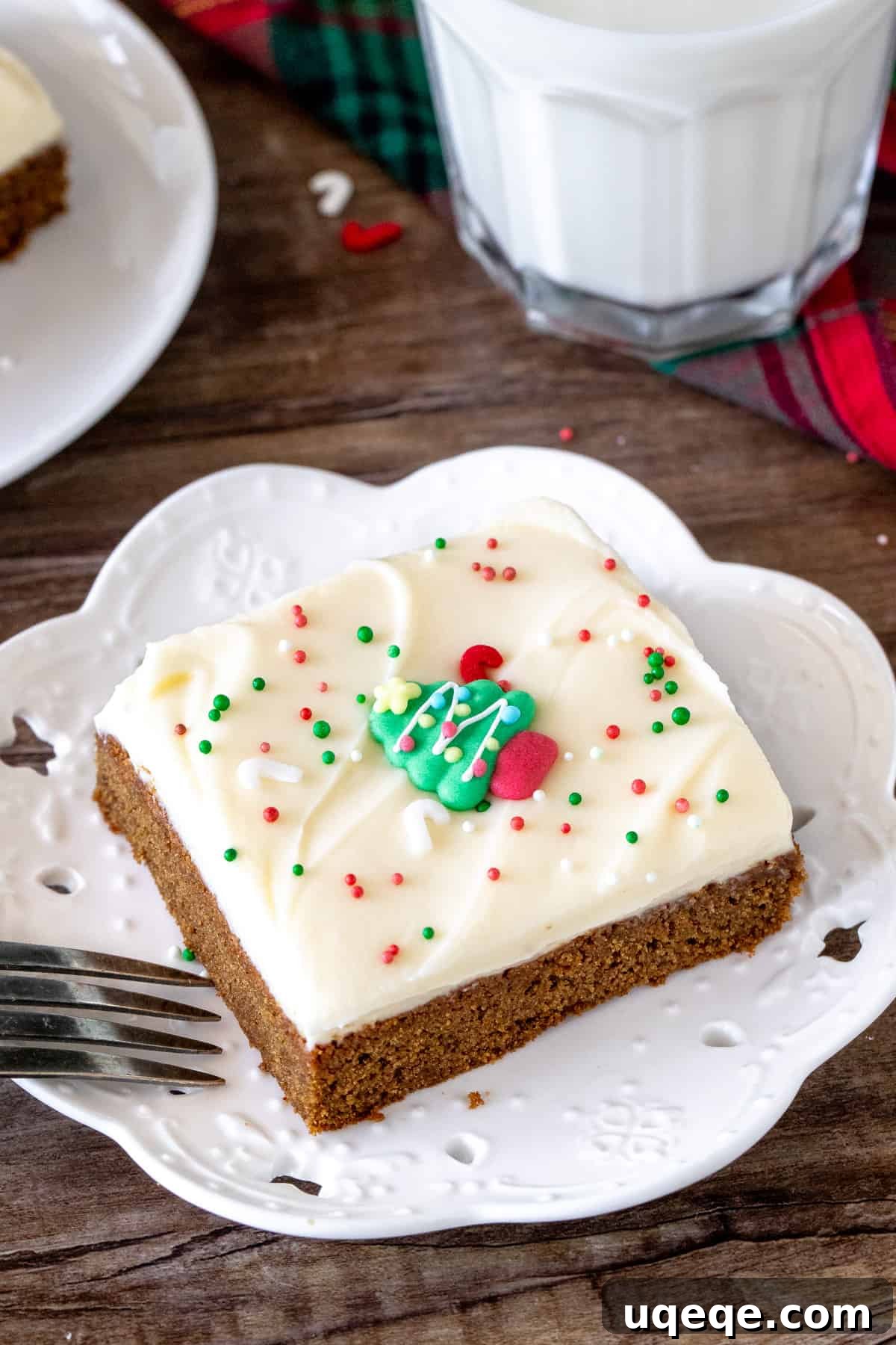 A close-up shot of a single slice of gingerbread bar with fluffy cream cheese frosting, showing its soft, chewy texture.