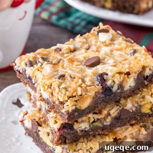 A stack of 3 Christmas magic cookie bars with a gingersnap crust and coconut topping.
