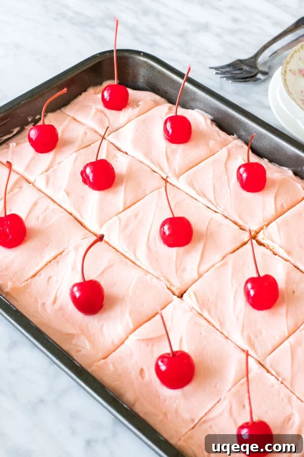 A 9x13 inch pan of maraschino cherry cake sliced into pieces.