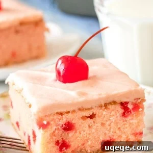 A slice of maraschino cherry cake with cherry frosting and a cherry on top