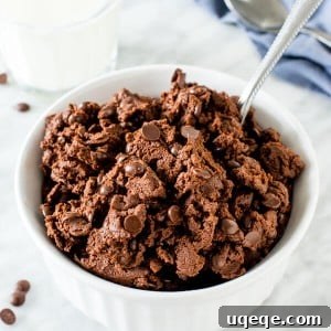 A bowl of edible double chocolate cookie dough with a spoon in it.
