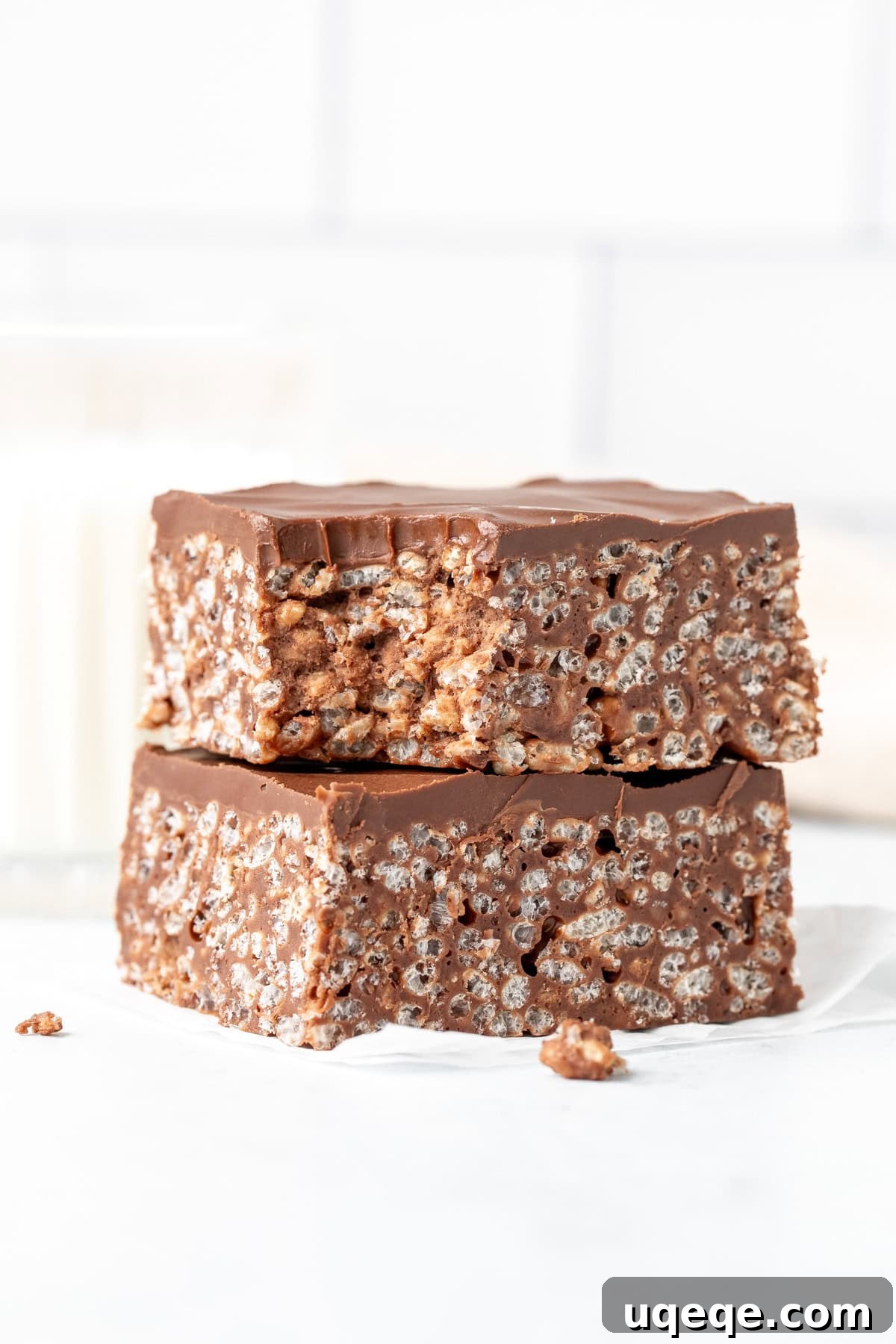 Decadent Chocolate Krispie Bars 6 Two perfectly cut chocolate Rice Krispie treats with a thick chocolate topping, stacked and showing a bite taken out of the top square, highlighting the gooey interior.