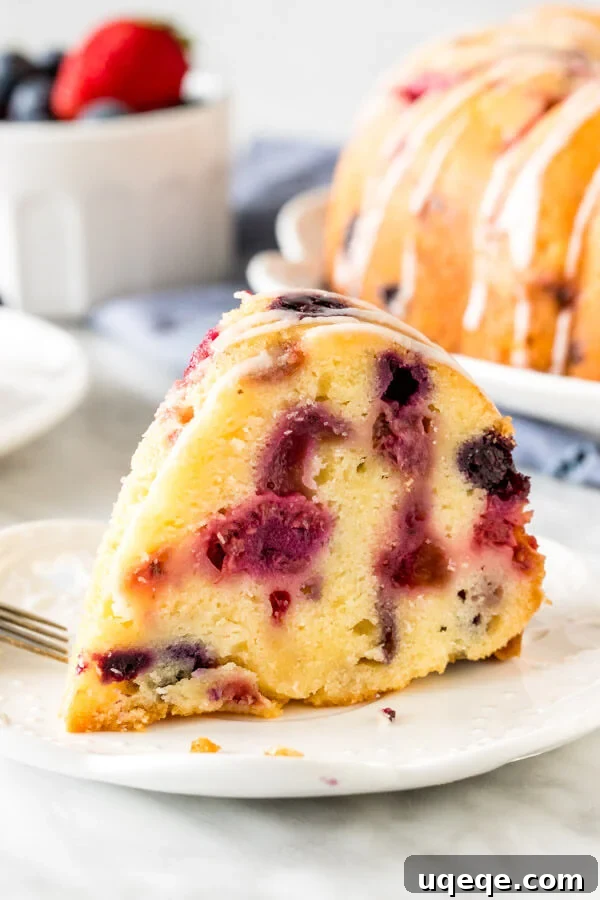 A perfectly sliced piece of berry pound cake on a plate, showcasing its moist interior and generous berry distribution.