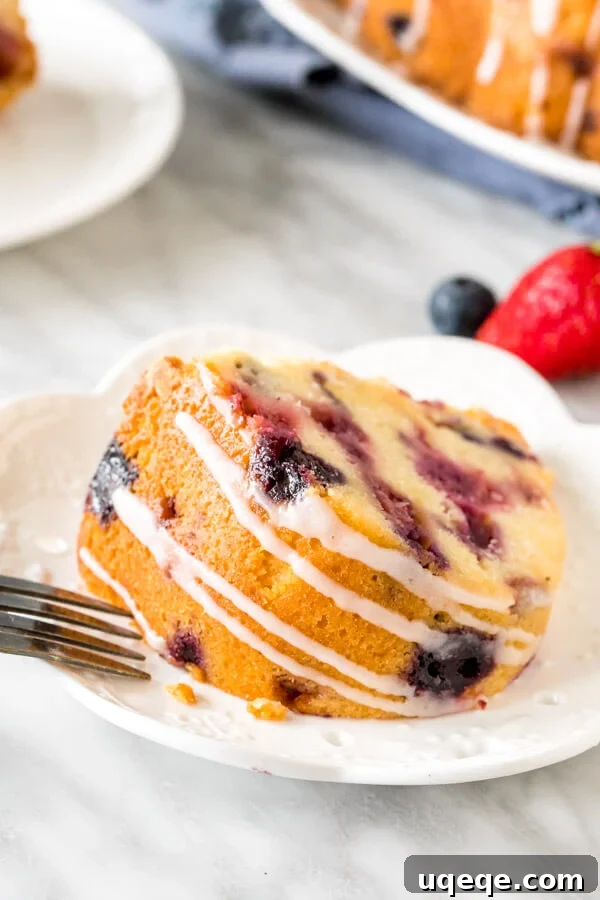 A slice of bundt cake with a delicate drizzle of glaze on its side, emphasizing the perfect crumb and fresh berries.