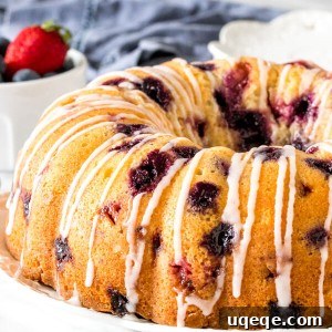 A berry bundt cake on a plate with a drizzle of glaze on top