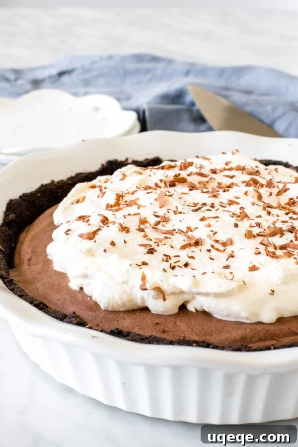 Silky Chocolate Mousse Indulgence 2 Chocolate mousse pie with Oreo crust and whipped cream topping in a white pie plate.
