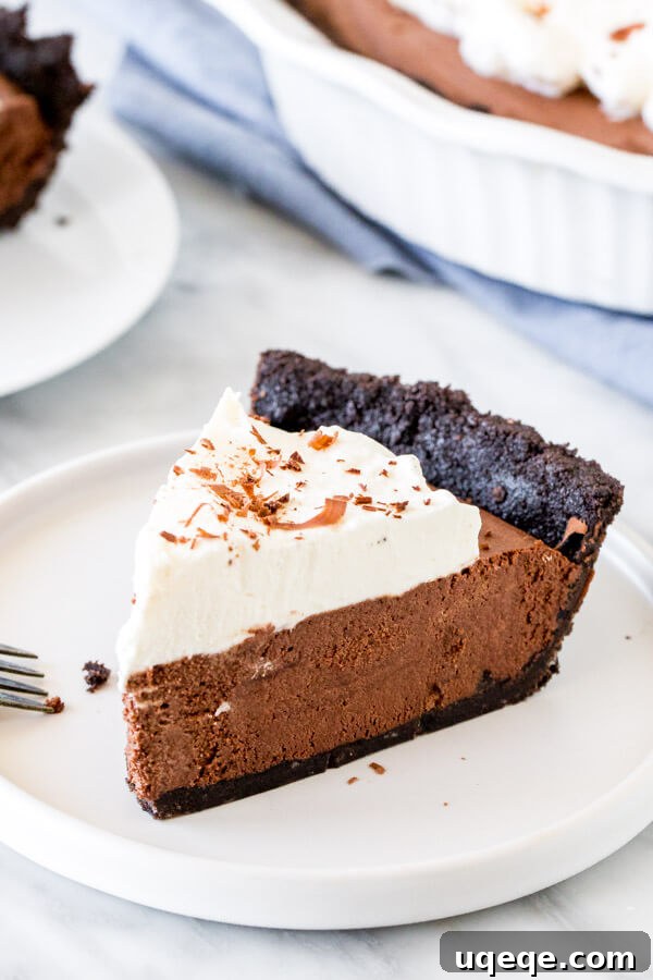 Silky Chocolate Mousse Indulgence 3 Slice of chocolate mousse pie with whipped cream on a white plate.