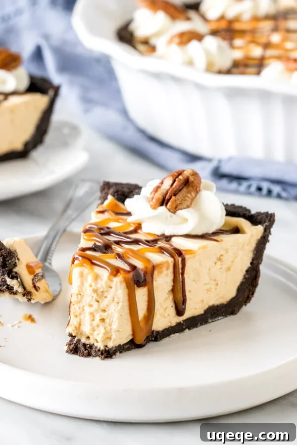 Irresistible Bite of No-Bake Turtle Pie A close-up view of a piece of No-Bake Turtle Pie, with a small bite taken out, resting on a white plate. The image clearly displays the distinct layers: the dark, crumbly Oreo crust, the smooth, light brown caramel cheesecake filling, and the rich caramel, chocolate, and pecan toppings, emphasizing its irresistible texture and taste.