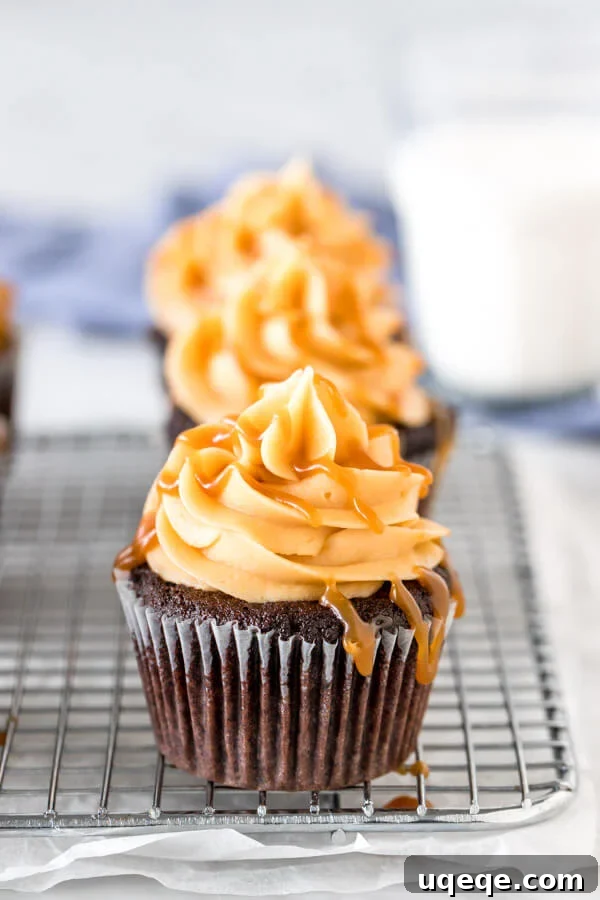 Chocolate cupcakes with caramel frosting drizzled with caramel sauce on a wire rack.
