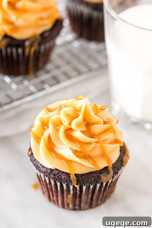 Cupcake topped with caramel buttercream and drizzled with salted caramel drizzled on top with a glass of milk.