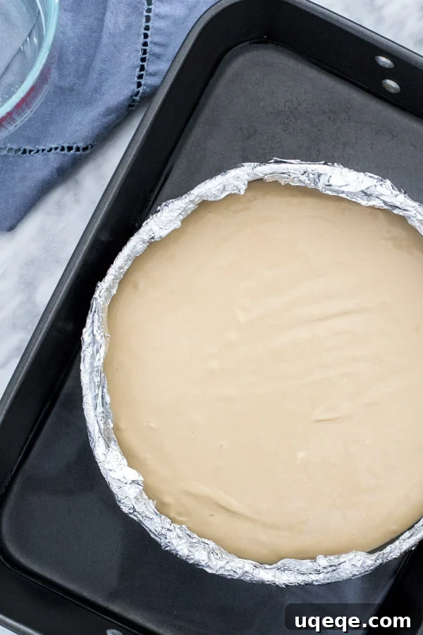 Decadent Coffee Cheesecake 4 Unbaked coffee cheesecake in water bath with the pan wrapped in aluminum foil.