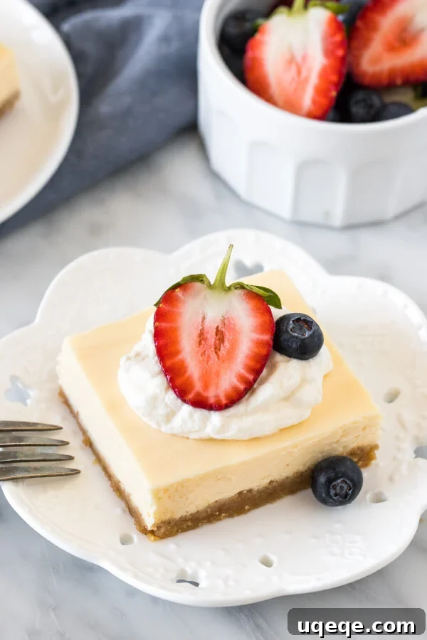 Decadent Cheesecake Bites 4 Cheesecake square on a plate, topped with cream and berries.