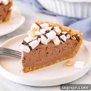 A beautiful slice of rocky road cheesecake pie, generously topped with mini marshmallows and a drizzle of chocolate.
