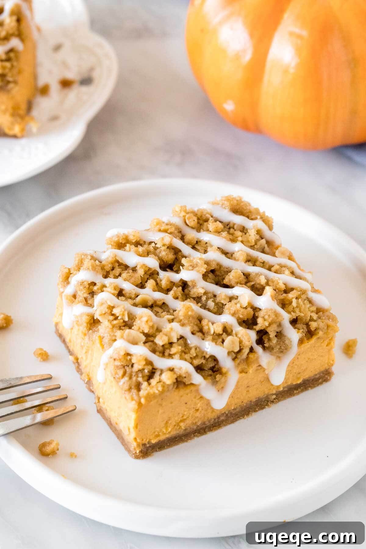 A close-up view of a single pumpkin streusel bar, showcasing its inviting oatmeal topping and a delicate drizzle of vanilla glaze, highlighting its rich texture and enticing autumn appeal.