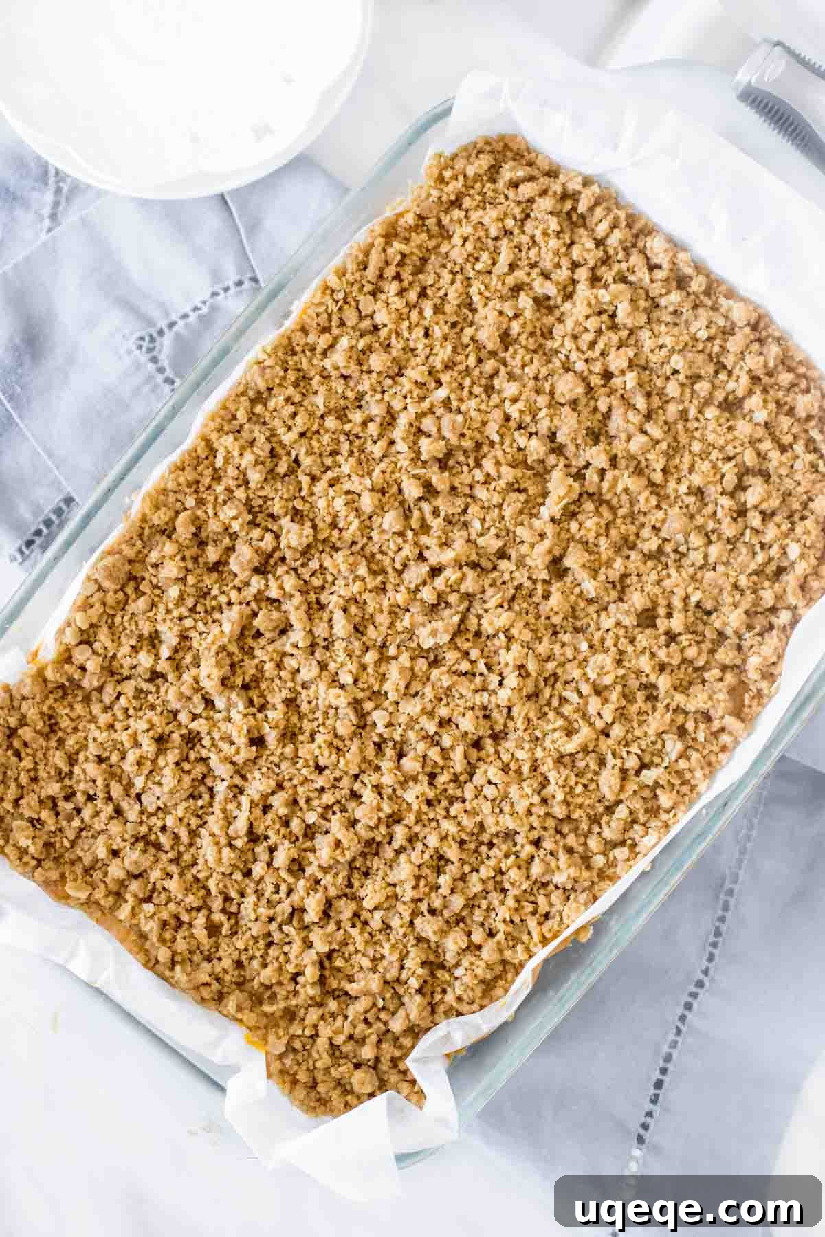 An overhead shot of a 9x13 inch pan filled with freshly baked pumpkin bars, glistening with a perfect golden streusel topping, ready to be cooled and enjoyed.