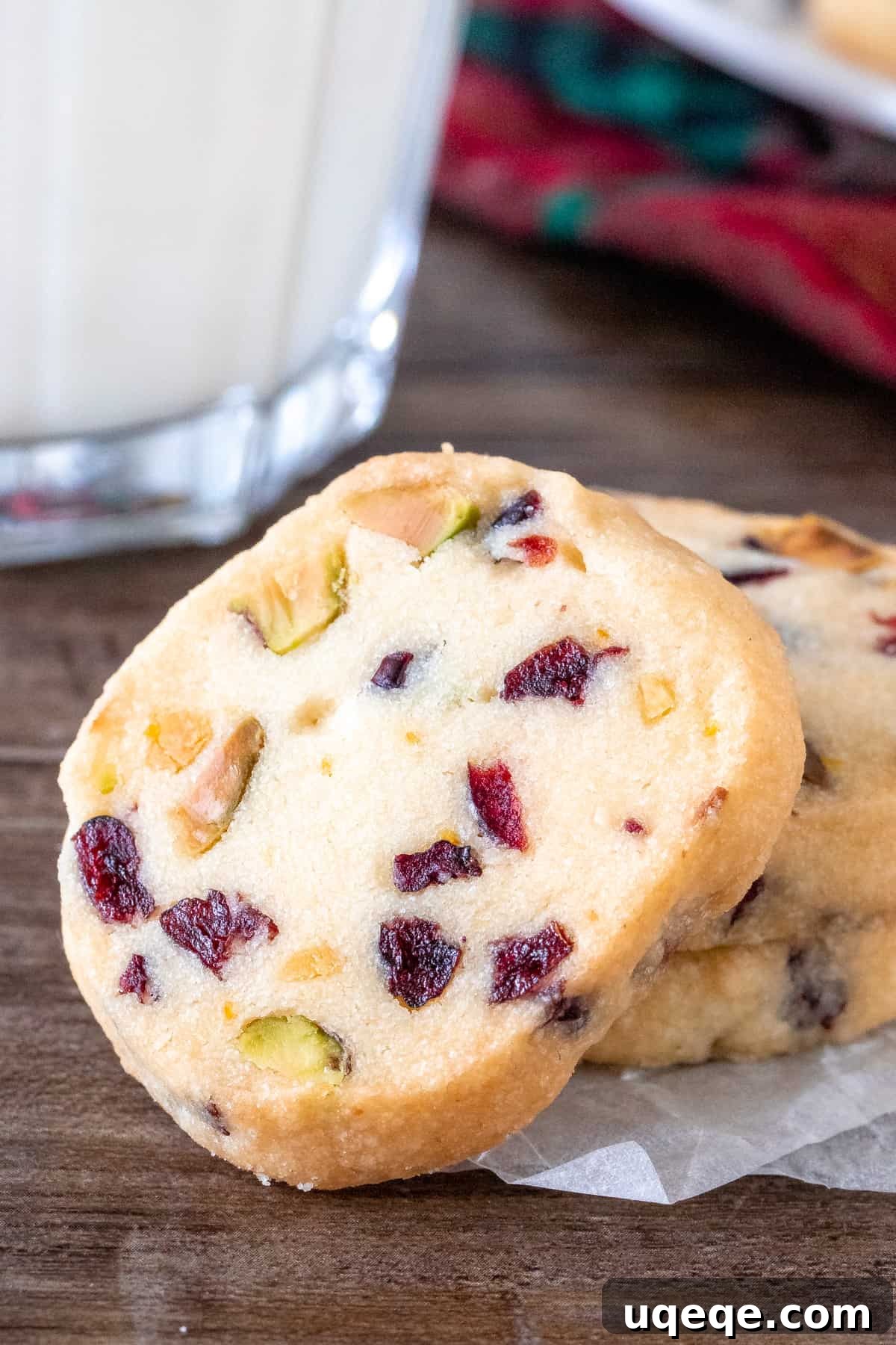 Jeweled Cranberry Pistachio Shortbread 2 A beautifully arranged stack of Cranberry Pistachio Shortbread cookies next to a glass of milk, highlighting their festive colors and inviting texture.