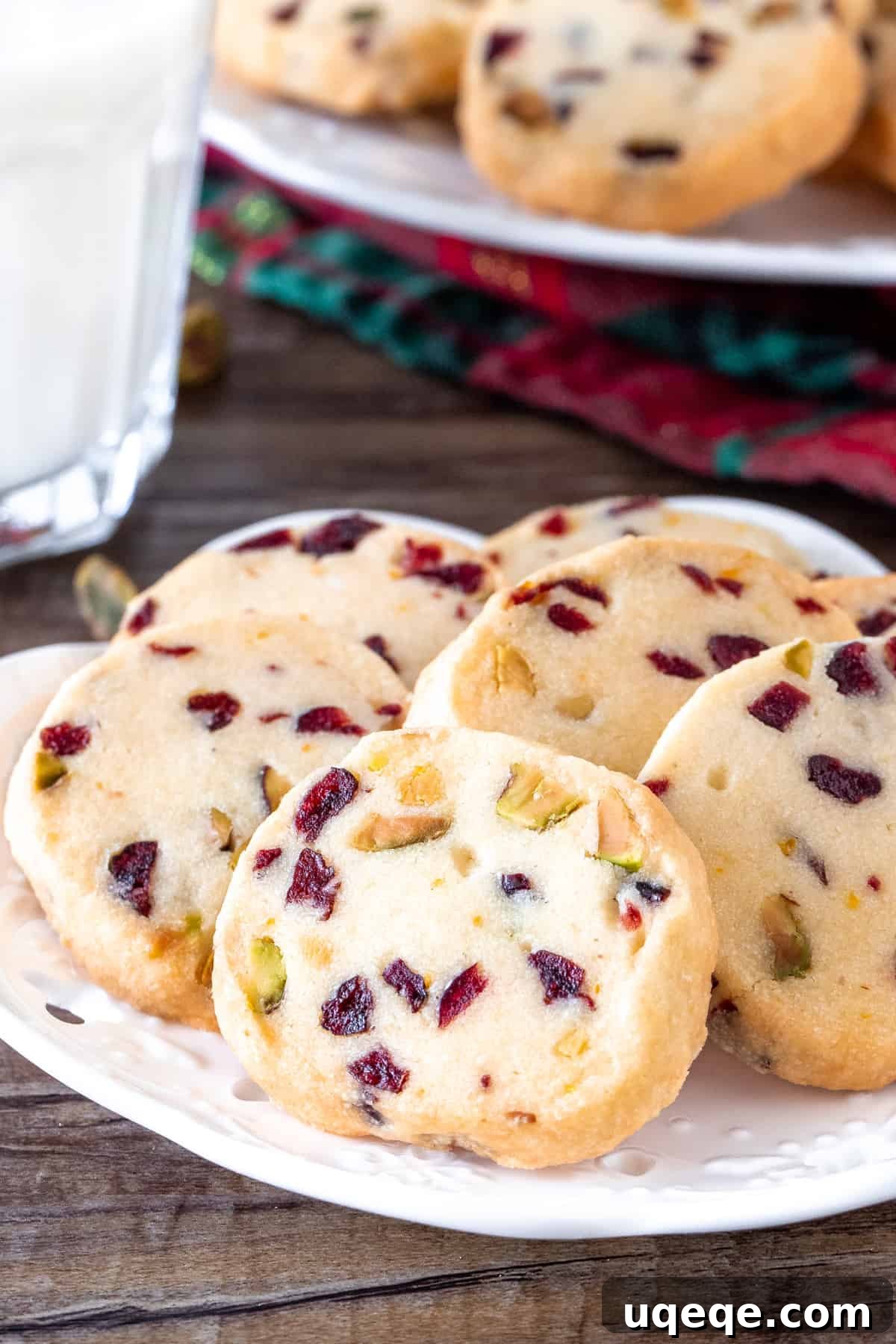 Jeweled Cranberry Pistachio Shortbread 5 A festive plate of Cranberry Orange Shortbread cookies with a glass of milk, invitingly arranged for a holiday treat.